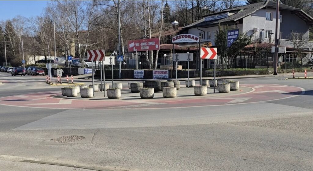 Kružni tok u Karlovcu Pod Švarčom – postojeći raspored cvjetnjaka Kružni tok Pod Švarčom u Karlovcu s označenom crvenom trakom i betonskim cvjetnjacima koji utječu na putanju vozila